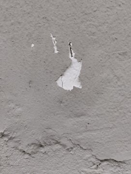 Close up of weathered gray concrete wall surface with peeling paint and rough cracked texture