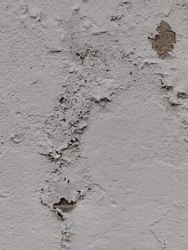 Detailed view of a weathered grey wall with peeling paint and crumbling concrete texture effect