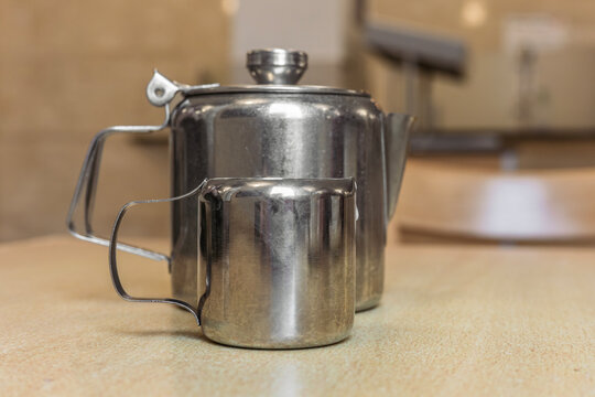 Stainless steel single-serve teapot and small milk jug on counte