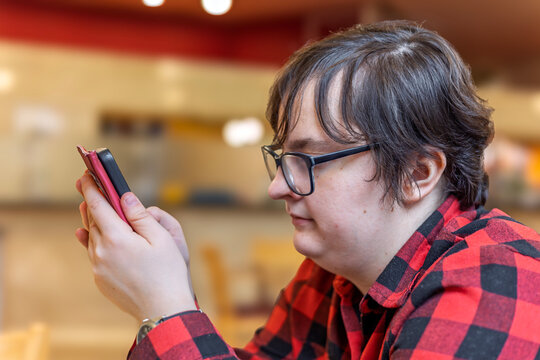 Young woman with Down syndrome using smartphone in cafe