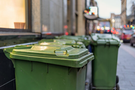 Row of green wheelie bins on city centre pavement
