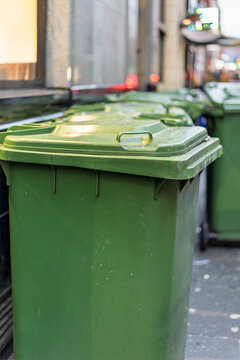 Row of green wheelie bins lined up in city centre alley