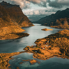 Vertical aerial view of a scenic fjord with wooden cabins and golden autumn mountains in northern Norway with copy space in sky © Quality by Simon