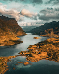 Vertical aerial view of a scenic fjord with wooden cabins and golden autumn mountains in northern Norway with copy space in sky © Quality by Simon