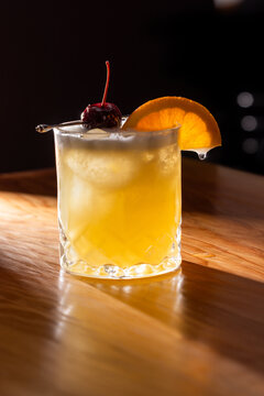 Beautiful Whiskey sour served on the rocks garnished with an orange slice and a dark cherry