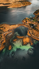 Vertical aerial top down view of turquoise clear water lagoon and autumn coast in northern Norway with copy space in ocean © Quality by Simon