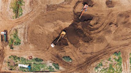 Excavator excavating sand and loading a truck at a construction site aerial earthmoving industry © VisualTreat12
