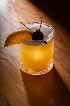 Beautiful Whiskey sour served on the rocks garnished with an orange slice and a dark cherry