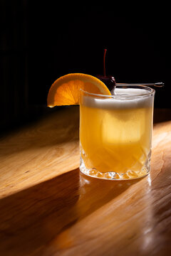 Beautiful Whiskey sour served on the rocks garnished with an orange slice and a dark cherry