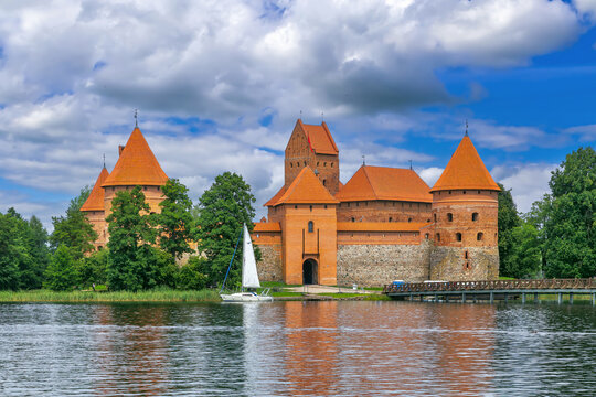 View of Trakai Island Castle from the lake in Lithuania. Red brick gothic architecture under partly cloudy sky