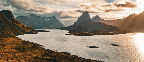 Panoramic aerial view of a dramatic mountain peak and fjord under golden sunlight in northern Norway © Quality by Simon