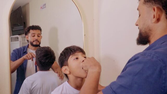 Father teaching son how to brush teeth
