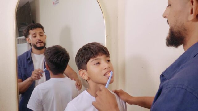 Father teaching son how to brush teeth