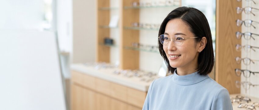 眼鏡店で新しいメガネを試着する日本人女性 コピースペース付き