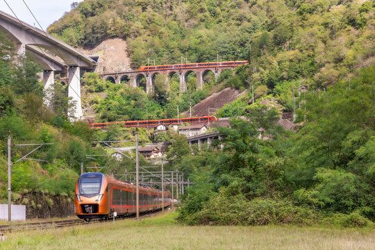 Red trains pass the historic Gotthard spiral loop tunnels, built in the 19th century, to overcome about 200 meter height difference. In the village Gironico the three levels of the tracks can be seen.
