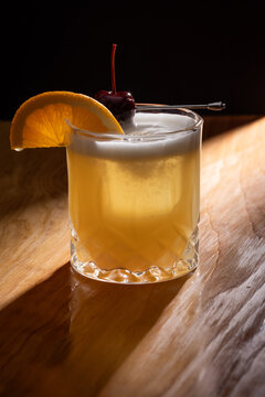 Beautiful Whiskey sour served on the rocks garnished with an orange slice and a dark cherry