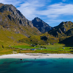 Aerial drone view of a white sand beach with turquoise water and green mountains under a blue sky in northern Norway © Quality by Simon