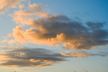 Fototapeta premium Sunlit clouds glow in warm evening colours above Saint Ives, Cornwall, England, with lone seagull crossing expansive coastal sky at sunset.