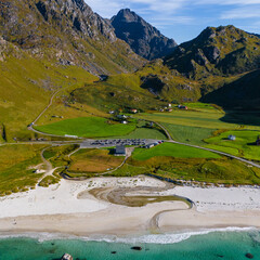 Vertical aerial view of a white sand beach with turquoise water and green mountains under a blue sky in northern Norway © Quality by Simon
