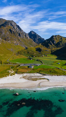 Vertical aerial view of a white sand beach with turquoise water and green mountains under a blue sky in northern Norway © Quality by Simon