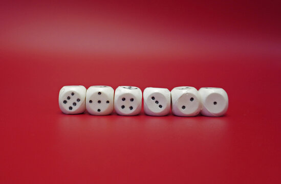 Six white dice with black dots are arranged in a row on the red surface. Each face shows a different number of points.