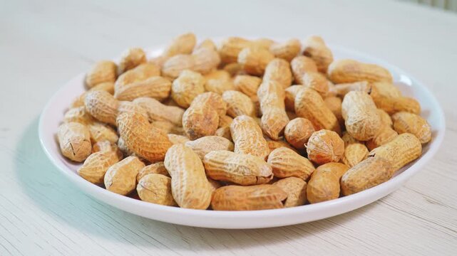 Whole Unshelled Peanuts Stacked on White Ceramic Plate
