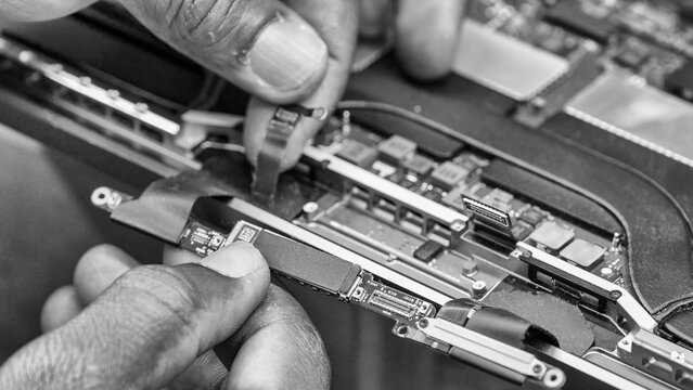 Repairing a laptop with visible internal components and circuit board at workbench