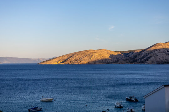 Rugged limestone hills near Stara Baska on Krk Island, Croatia, illuminated by warm golden hour sunlight above the Adriatic coast.