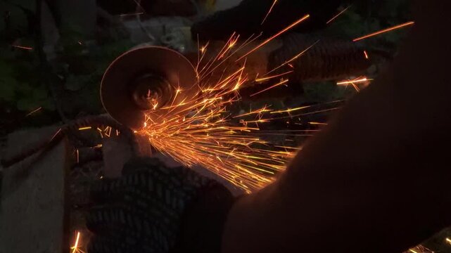 Man Cutting Metal with Angle Grinder, Sparks Flying in Workshop. Metalworking process in a workshop, suitable for construction, fabrication, welding, repair, engineering, and DIY projects.