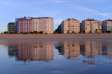 Obraz premium Sunset over Zurriola beach with city reflection on wet sand, San Sebastian, Basque Country, Spain