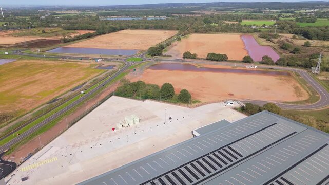 Aerial reverse view of a major logistics hub being built in the UK with new roads built and empty future plots