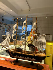 Vintage wooden model ship with white sails, antique nautical sailing vessel replica, handcrafted miniature sailboat on display stand © Izla
