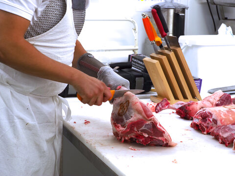 D&eacute;coupe de viande d'agneau sur une planche de d&eacute;coupe - Viande d&eacute;coup&eacute;e avec un couteau &agrave; viande, avec un gant type cote de maille pour se prot&eacute;ger.