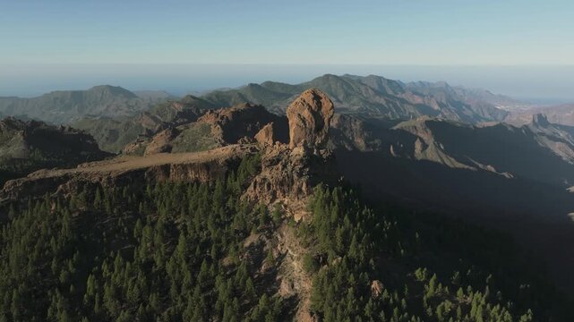 Aerial close-up of Roque Nublo monolith rising above pine forest, Gran Canaria