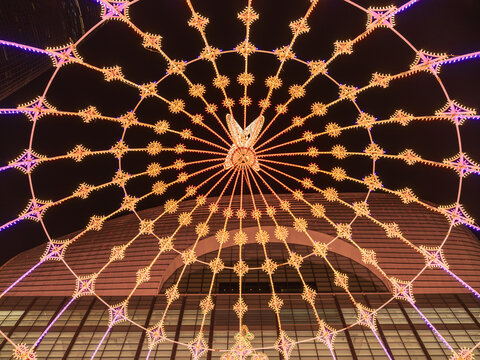View of festive illuminated light installation forming a web-like pattern against a modern building facade at night in Seoul, Seoul, South Korea.