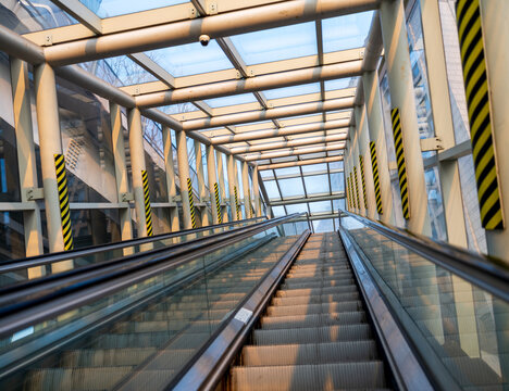 View of an escalator inside a modern glass-enclosed walkway with steel beams and yellow-black safety markings in Seoul, Seoul, South Korea.