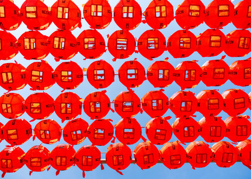 View of rows of vibrant red lanterns hanging against a clear blue sky in Seoul, Seoul, South Korea.
