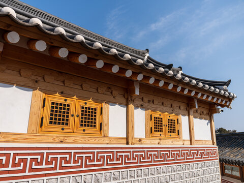 View of the traditional tiled roof and wooden architecture of a hanok in Bukchon Hanok Village with intricate lattice windows and stone wall base in Seoul, Seoul, South Korea.
