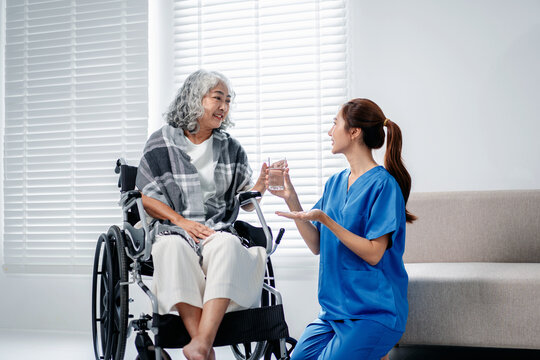 Professional caregiver offering hydration to senior woman in whe