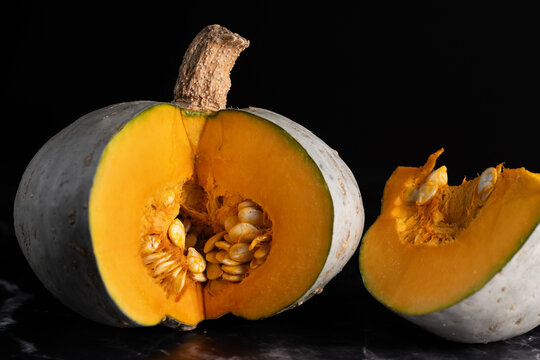 Close-up of a green pumpkin with orange flesh. The pumpkin has been cut open. The seeds are visible inside.