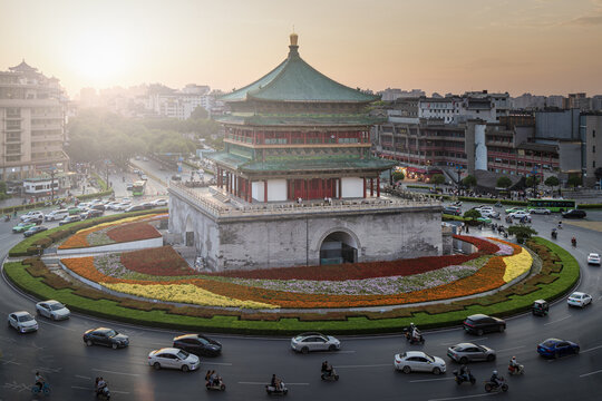 View of the Bell Tower of Xi'an surrounded by a vibrant circular flower bed and busy traffic at sunset in Xi'an, Shaanxi, China.