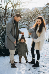 Fototapeta na wymiar Family of four enjoying winter day in snowy garden