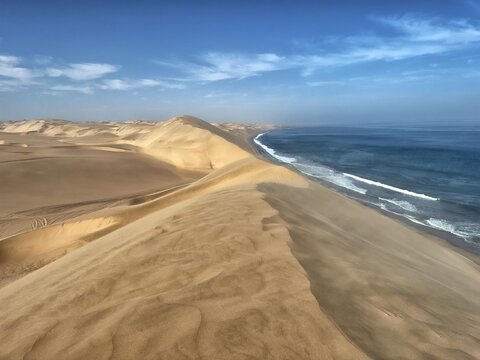 View of the Skeleton Coast where vast golden sand dunes meet the Atlantic Ocean in the Kunene Region, Namibia.