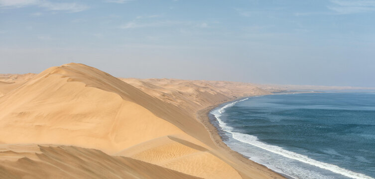 View of the vast sand dunes of the Skeleton Coast meeting the Atlantic Ocean in Kunene Region, Namibia.