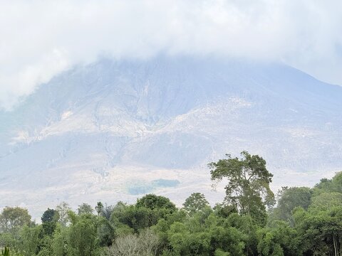 Majestic Mount Sinabung volcano covered in clouds above a tropical forest landscape in Berastagi Karo North Sumatra.