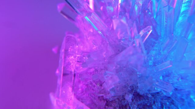 A real crystal. The grown crystal rotates on an illuminated turntable. A scientific experiment and chemical study. A beautiful background or screensaver. Pink and blue.