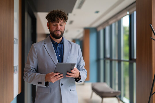 Businessman using digital tablet in office hallway