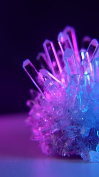 A mysterious, magical, genuine crystal. The grown crystal rotates on an illuminated turntable. A scientific experiment and chemical study. A beautiful background or screensaver. Blue and pink.