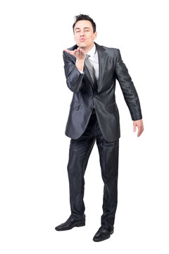 Full body of seductive male in elegant suit looking at camera while sending air kiss isolated on transparent background in light studio