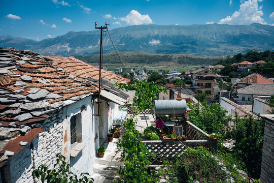 Stone houses with terracotta roofs in Albanian mountain village, real lifestyle travel illustration with scenic view in Gjirokaster, Albania.